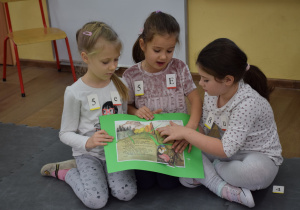 Trzyosobowy zespół dzieci prezentuje ułożone puzzle